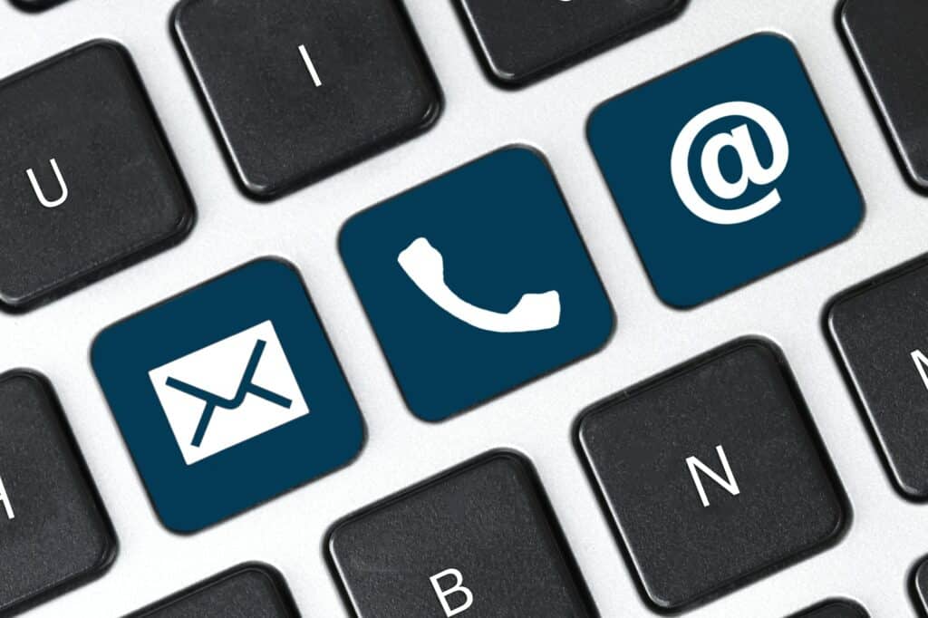 Gros plan d'un clavier montrant des touches avec des symboles pour une enveloppe, un téléphone et un arobase (@), représentant respectivement l'e-mail, la communication téléphonique et l'adresse e-mail.