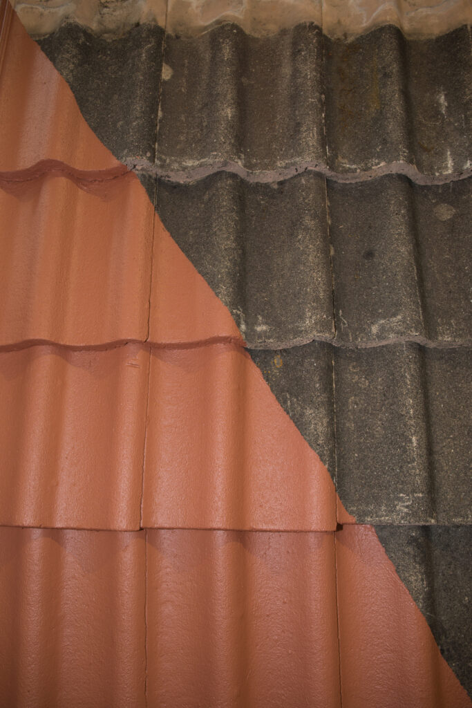 Gros plan d'un toit de tuiles présentant des sections de tuiles propres et rouge vif contrastant avec des tuiles sombres, altérées et sales, illustrant les résultats d'un nettoyage approfondi de toiture à Prayssac.