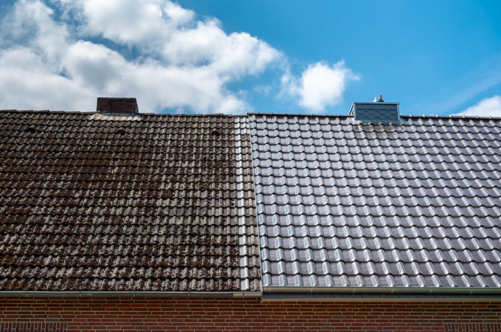 Un toit présentant un contraste net entre les vieilles tuiles couvertes de mousse à gauche et les tuiles propres nouvellement remplacées à droite, reflétant le récent nettoyage de toiture à Biars-sur-Cère, sur un ciel partiellement nuageux.