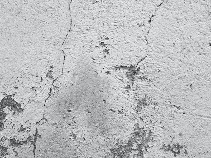 Une vue rapprochée d'un mur blanc patiné avec des fissures et de la peinture écaillée.